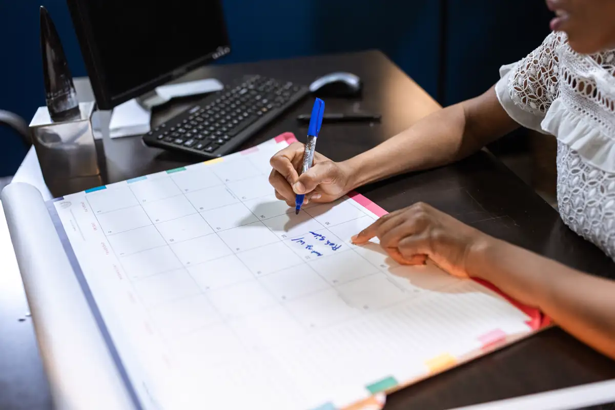 Hand writing an appointment on a desk calendar in an office