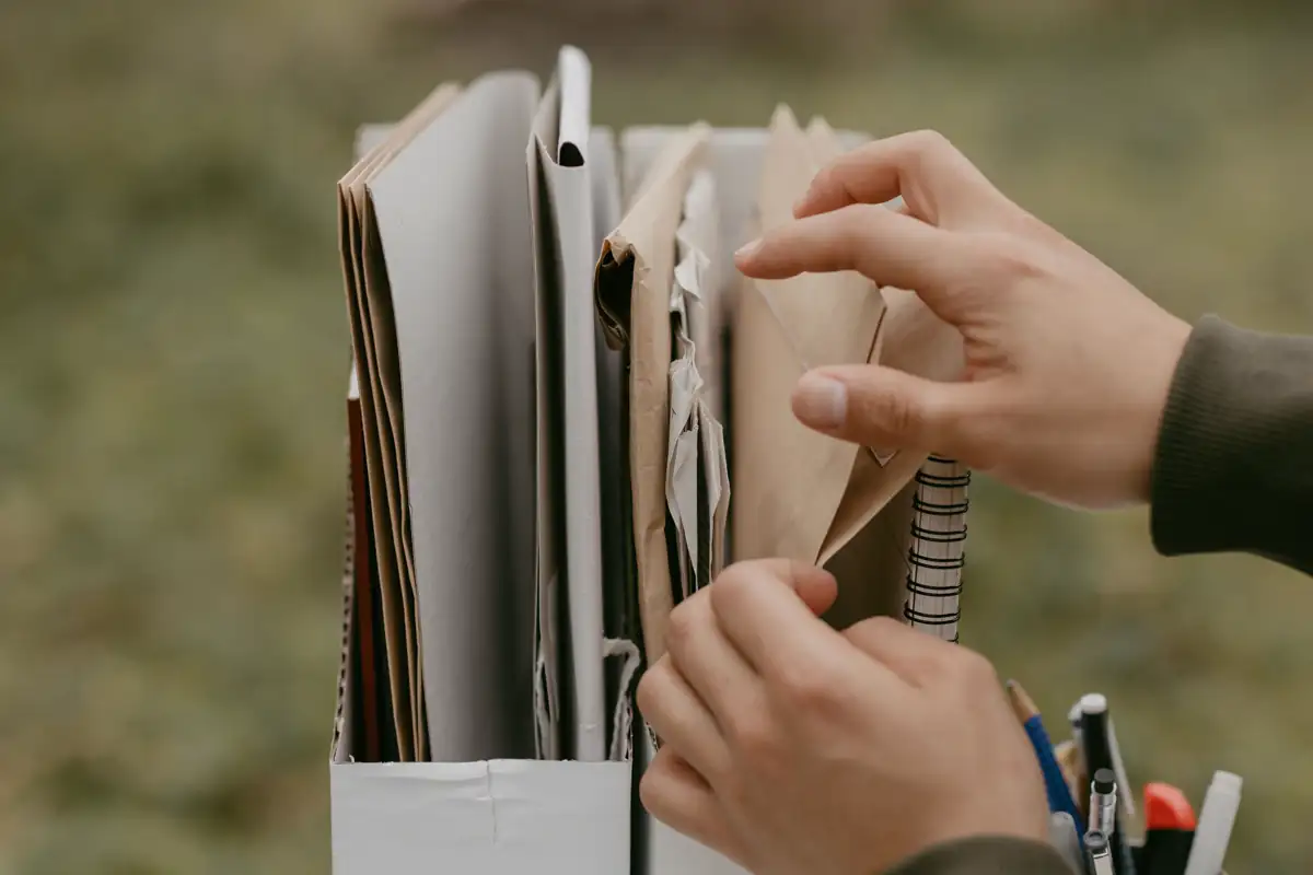 Hands organizing envelopes and folders in a document box