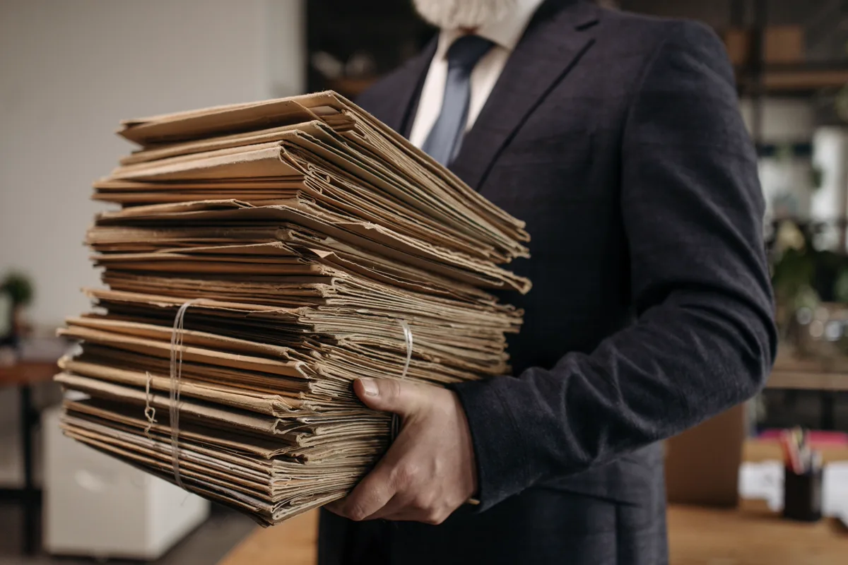 Person carrying a stack of organized paper file folders