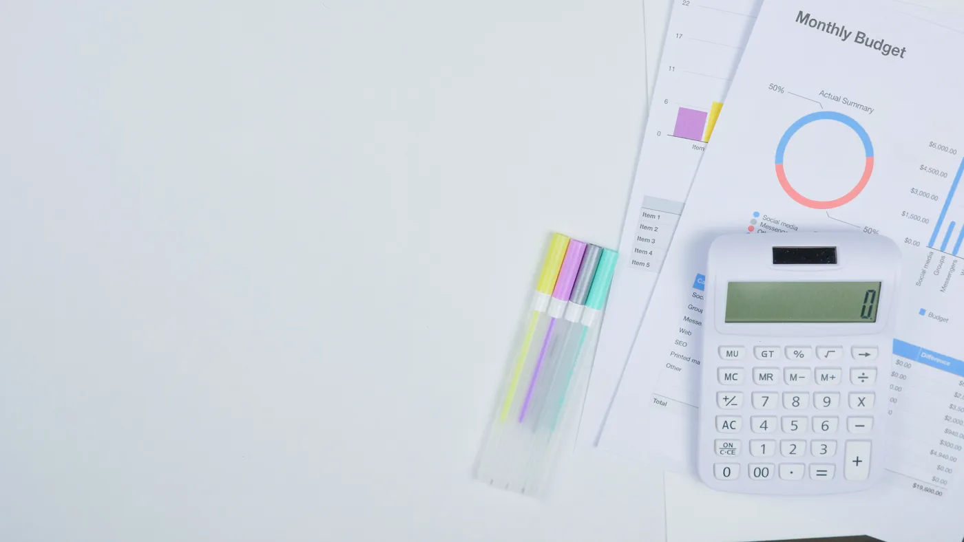Calculator beside financial planning documents and pens on a desk
